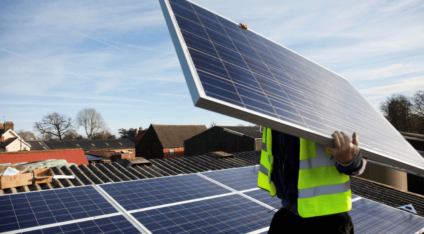 man holding solar panel to install on roof